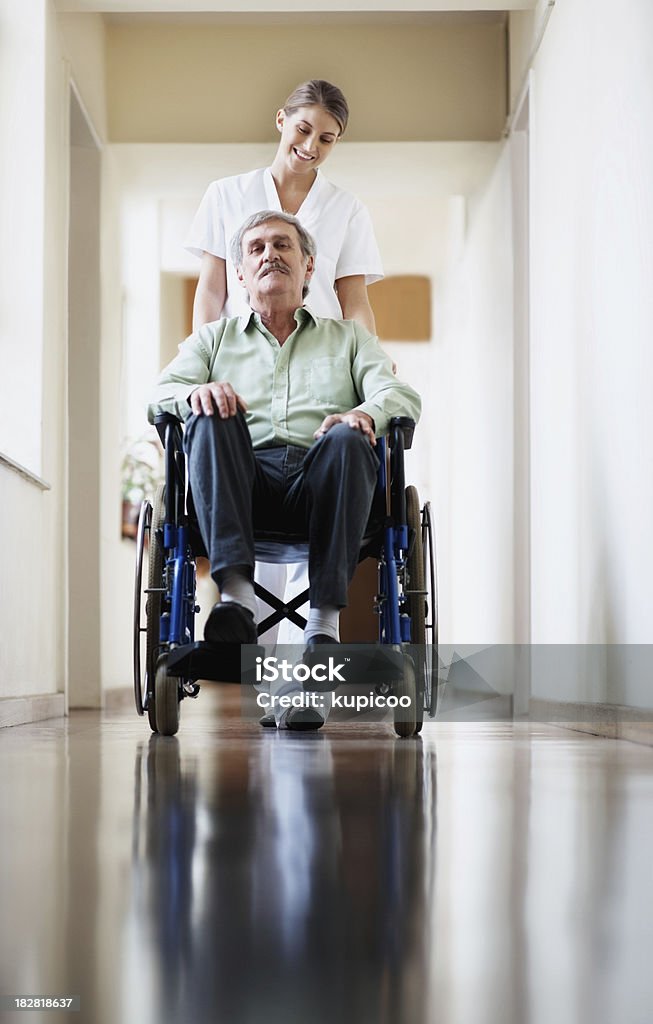 Enfermeira empurrando o homem sênior em cadeira de rodas de estar - Foto de stock de Cadeira de rodas - Equipamento Ortopédico royalty-free