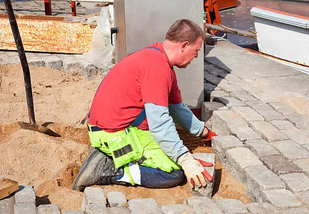 Paver working on his knees setting granite paving stones, Stockholm, Sweden.