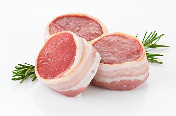 Filet mignon wrapped in bacon and a sprig of rosemary Fillet Mignon Cut Wrapped with Baconhttp://i1215.photobucket.com/albums/cc503/carlosgawronski/FoodonWhite.jpg uncooked bacon stock pictures, royalty-free photos & images