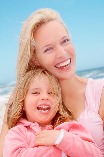 istock Beautiful female with her smiling daughter at beach 182819308