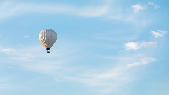 A lonely hot air balloon floats above the clouds.