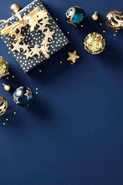 istock Dark blue vertical Christmas background with gift box, chic decorations, luxury golden balls. Flat lay, top view. 1828193888