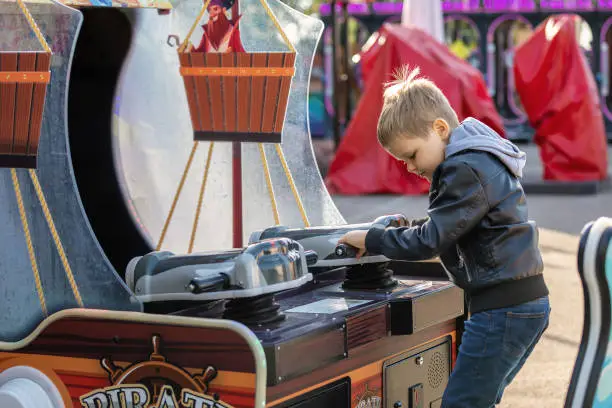 Little boy play with the cannon slot machine in an amusement park.