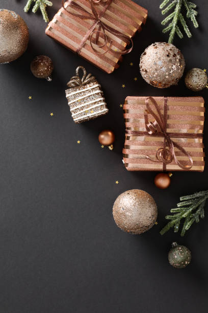 istock Christmas gift boxes with bronze baubles and fir branches on dark background. Flat lay, top view 1828198342