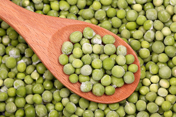 istock Frozen green peas in a wooden spoon 182819862