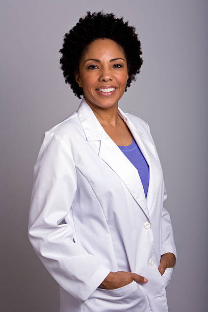 African ethnicity female wearing lab coat hands in pockets Mature African American female wearing lab coat hands in pockets african american scientist stock pictures, royalty-free photos & images