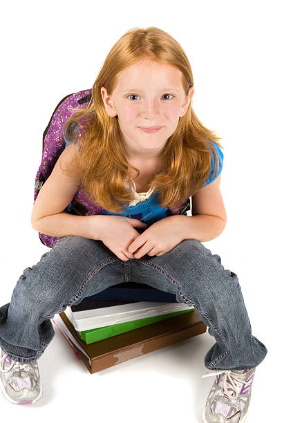istock Red-headed schoolgirl sitting on books 182820291