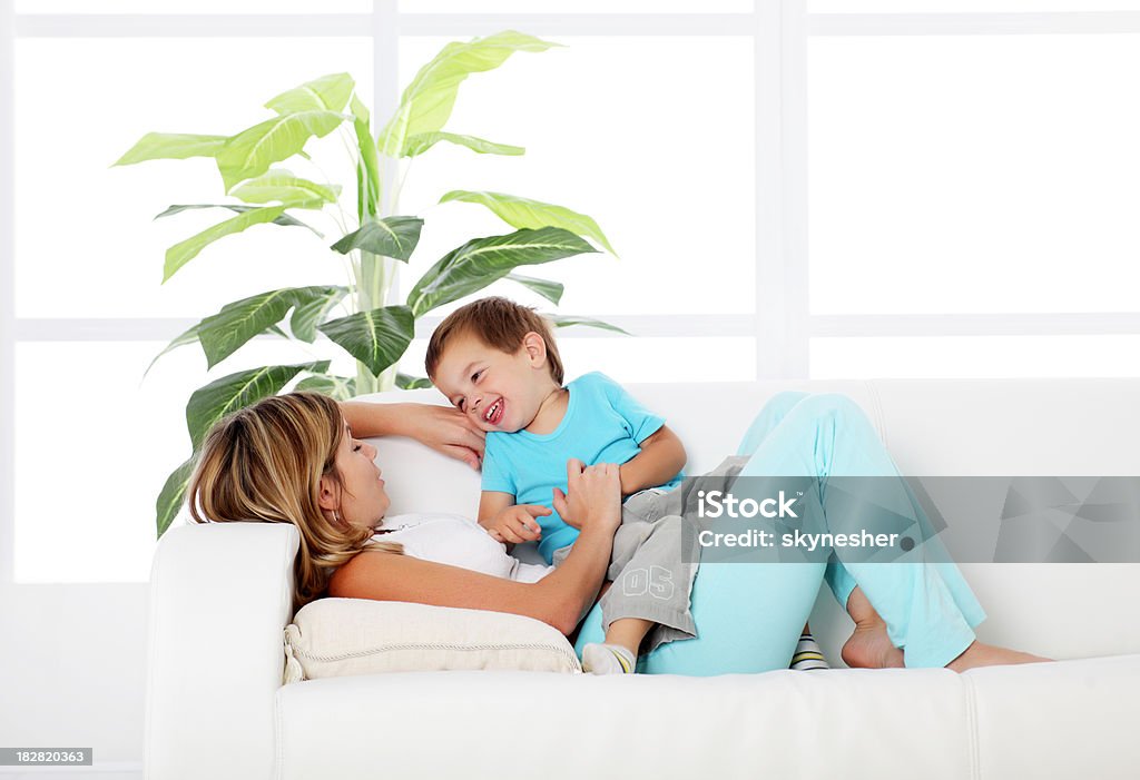 Madre con su pequeño hijo jugando en el sofá. - Foto de stock de Bebé libre de derechos