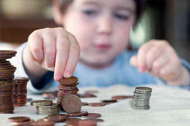 A young boy counting his piggy bank money A three year old child stacks pennies. Narrow depth of field. UK counting coins stock pictures, royalty-free photos & images