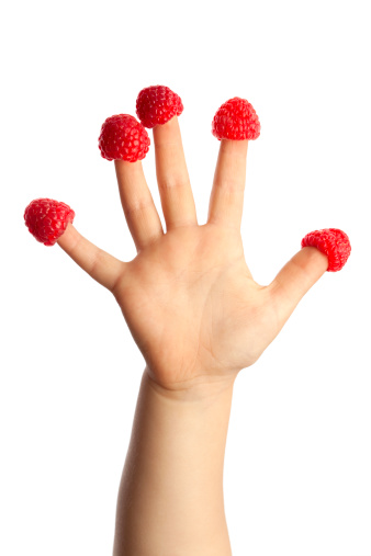 Child's hand with raspberries on fingers