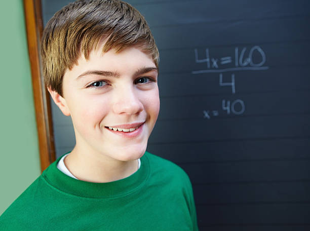 istock Portrait of a smiling young boy against black board 182821934