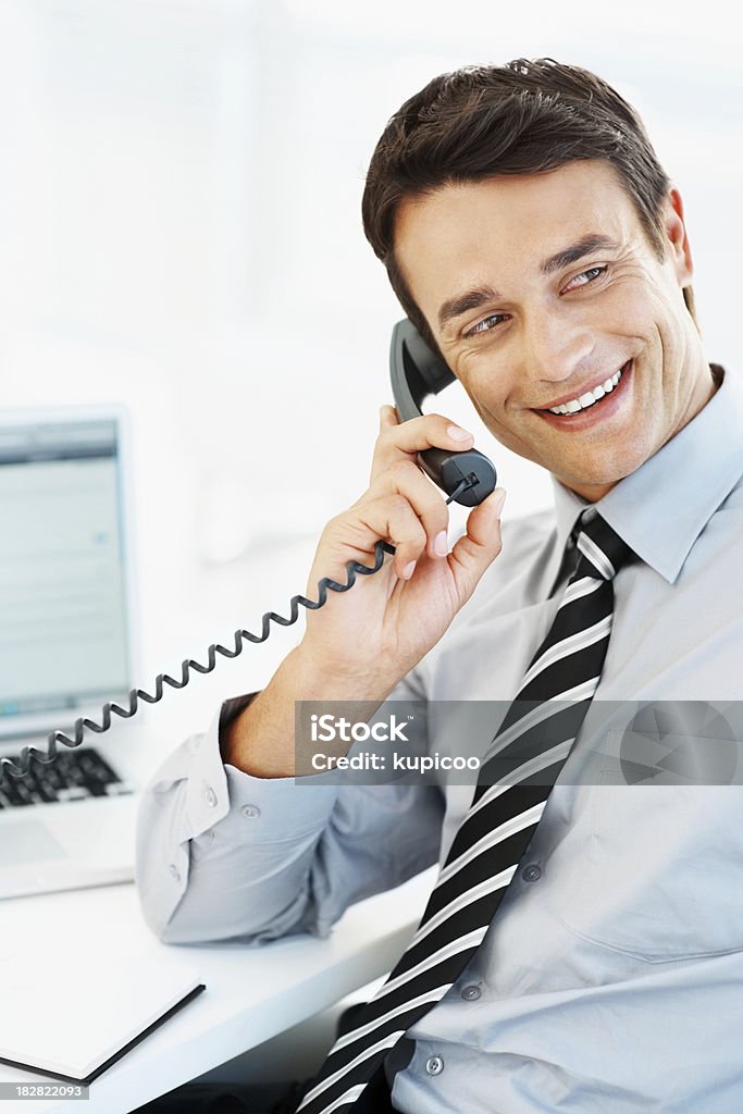 Sonriente atractivo hombre de negocios hablando por teléfono en la oficina - Foto de stock de 30-34 años libre de derechos