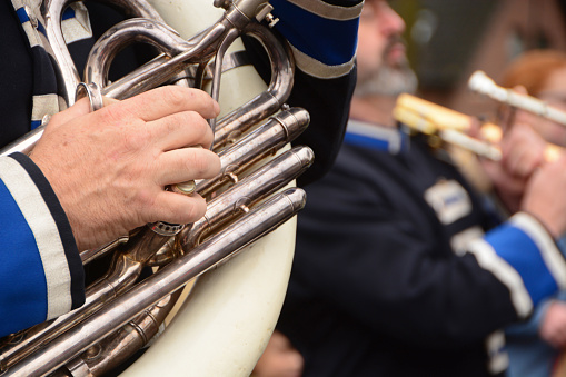 Part of a brass band with a human hand on the Tuba.