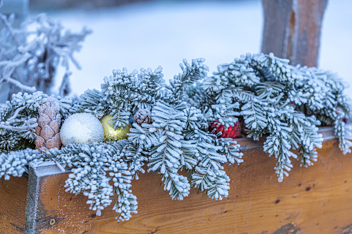 Christmas decoration from fir branches, colorful balls and pine cones covered with frost. Close up.