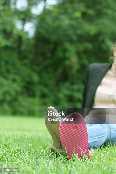Foto de Jovem Mulher Sentada Na Grama Com Dois Calçados Diferentes e mais fotos de stock de Ajardinado