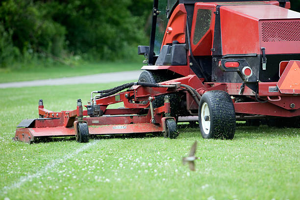 Commercial Lawn Mower Cutting Soccer Field Near Walking Path  commercial landscaping stock pictures, royalty-free photos & images