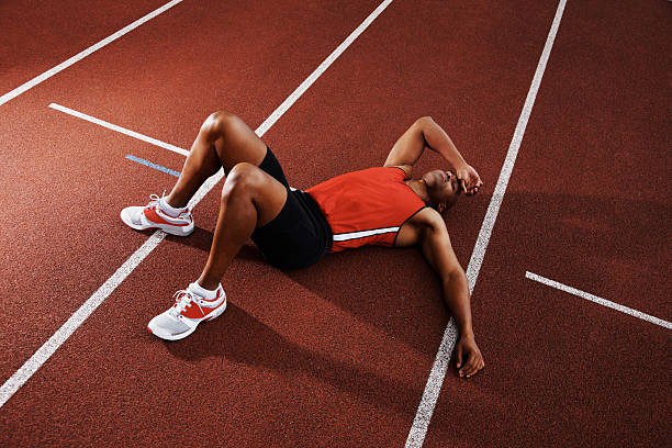 усталый спортсмен человек, лежа на беговая дорожка-лёгкая атлетика - men sleeping african descent shoe стоковые фото и изображения
