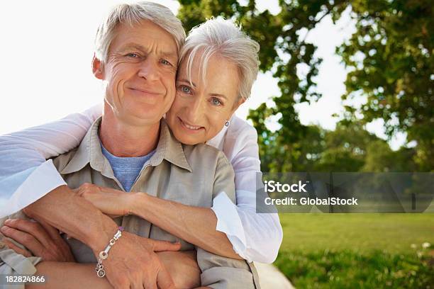 Sonriente Mujer Senior Que Enaltece Su Esposo Desde Atrás Foto de stock y más banco de imágenes de 55-59 años