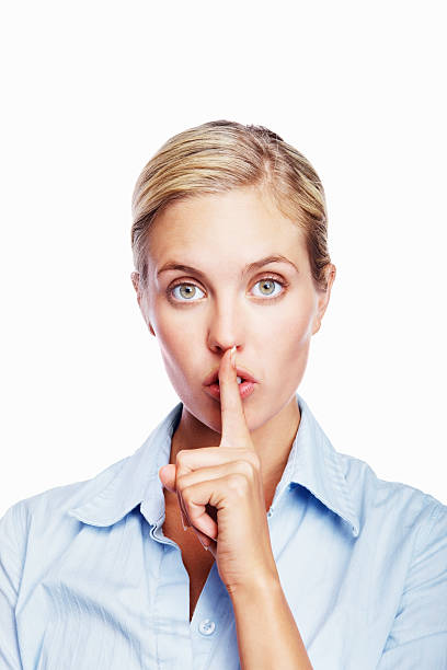 istock Business woman gesturing a silence sign against white 182825706