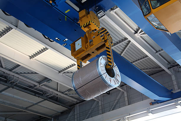 A large mechanical crane with a huge steel coil
