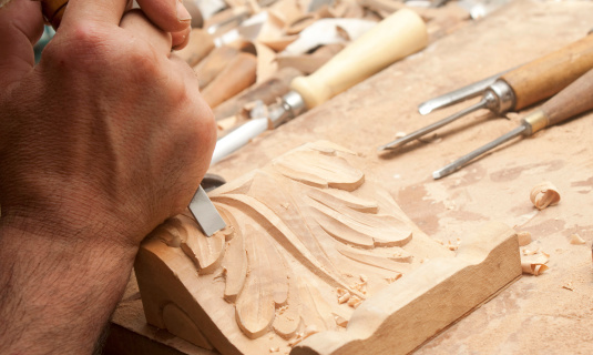 A carpenter is carving a piece of furniture