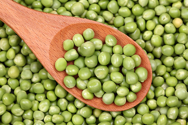 istock Fresh green peas in a wooden spoon 182826068