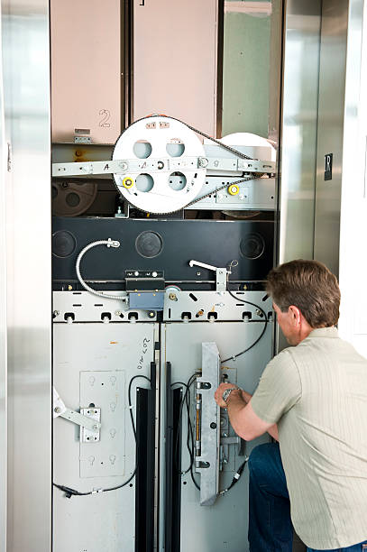 istock Tech working on the mechanical parts of an elevator 182826086