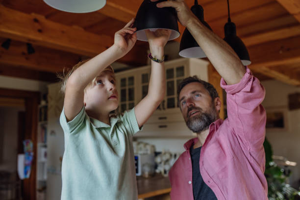 istock Father explaining led bubls to son, teaching him about energy efficiency, longevitiy and environmental impact. Changing bulbs at home. 1828267911