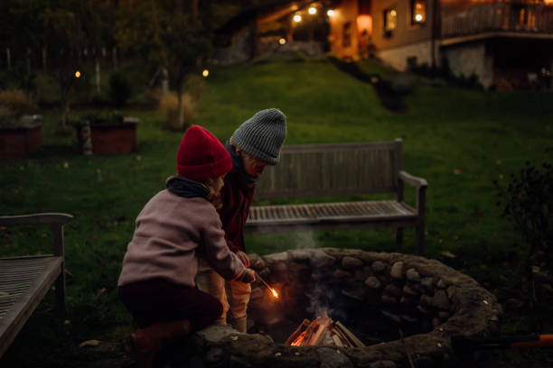 istock The family spending evening outdoors, lighting fire in a fire pit. Prents and kids spending quality family time together. 1828269539