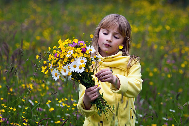 Children's day & childhood concept. Happy little blond girl runs & plays in buttercups meadow, having fun outdoors, connecting with nature. People and nature.