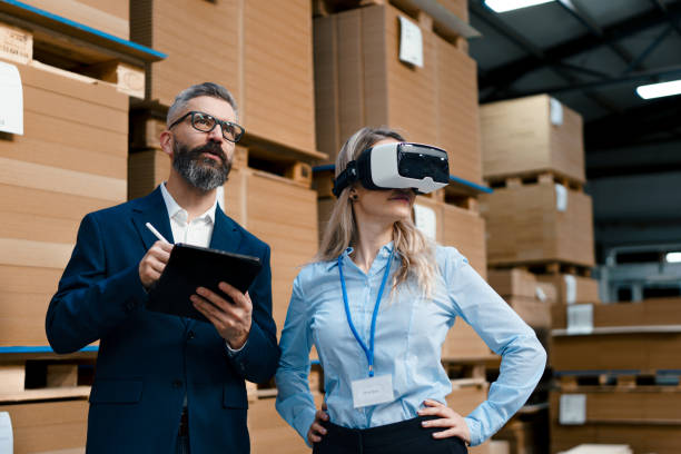 istock Warehouse managers talking logistics using VR, controlling stock levels. Virtual reality in inventory management. Smart glasses guiding female manager through warehouse, recording tracking data and quicken picking process. 1828297646