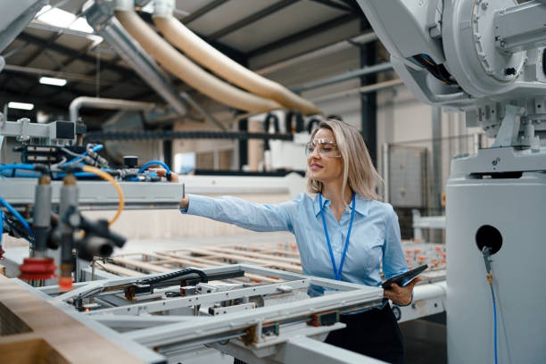istock Female engineer in modern industrial factory, checking robotic arm, controling process and manufacturing equipment or machinery. Manufacturing facility with robotics and automation. 1828299820