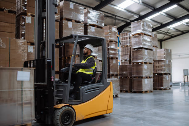 istock Multiracial warehouse worker driving forklift. Warehouse worker preparing products for shipmennt, delivery, checking stock in warehouse. 1828306679