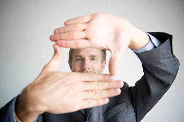 Businessman Looking through Frame with Hands Businessman frames the camera view with his hands determination focus the bigger picture human hand stock pictures, royalty-free photos & images