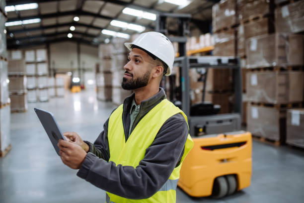 istock Warehouseman with tablet checking delivery, stock in warehouse. Warehouse manager using warehouse management software, app. 1828311458
