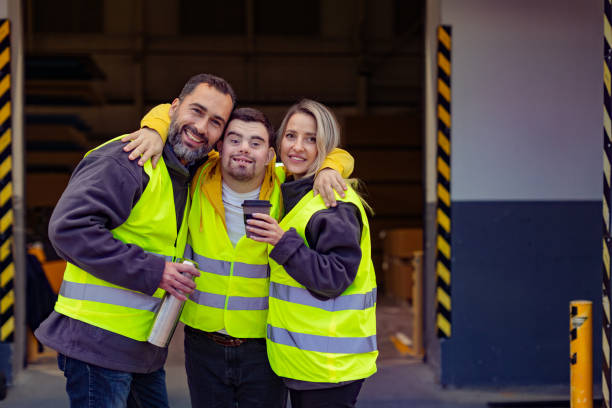 istock Man with Down syndrome and his colleagues taking break from work, drinking coffee, hot tea outdoors, on loading dock. Concept of workers with disabilities, support in workplace. 1828314143