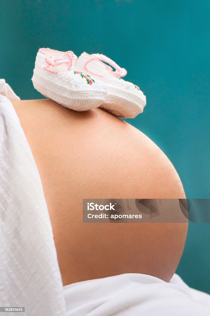 Baby shoes on pregnant woman belly Baby shoes on pregnant woman belly - Baby girl. 20-29 Years Stock Photo