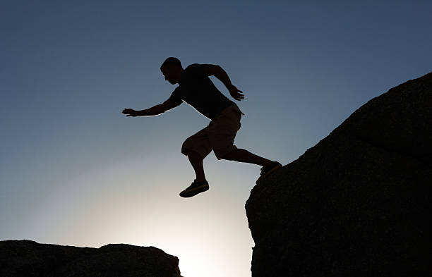istock Silhouette image of a man jumping from cliff 182831778