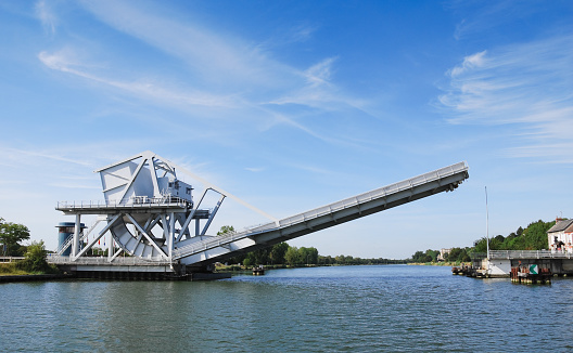 The modern replacement for the famous Pegasus Bridge in Normandy, France.  The bridge crosses the Caen canal that runs between Caen and Ouistreham.  Also known as Benouville bridge.  The bridge is a rolling bascule design, sometimes referred to as a drawbridge.