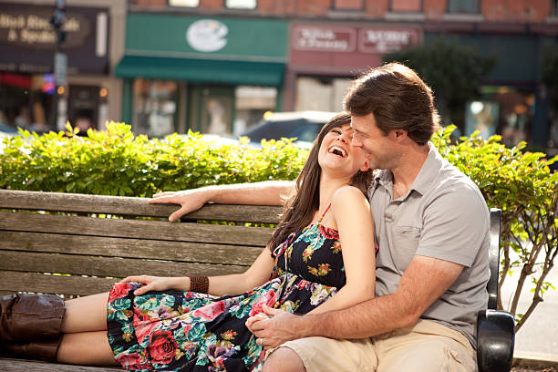 istock Happy Young Couple Sitting on Bench Downtown and Laughing 182833374