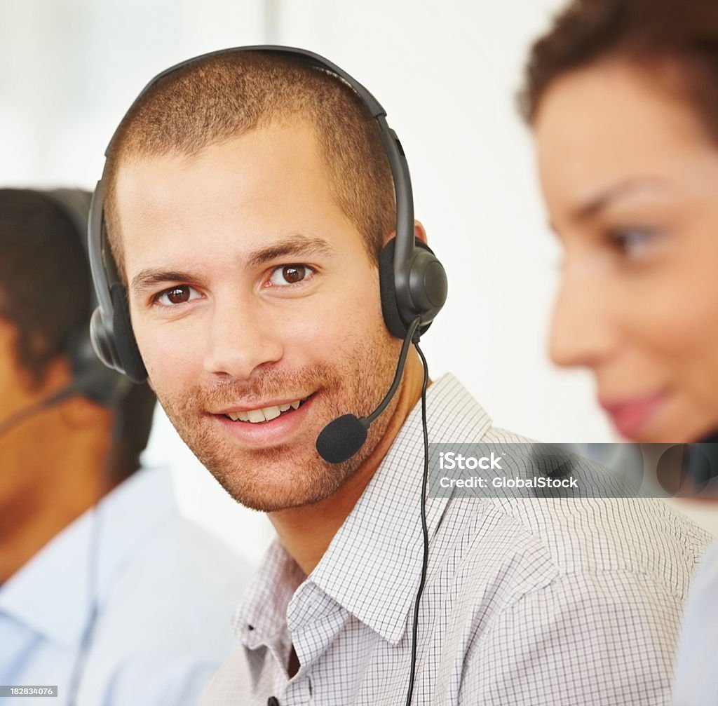 Uśmiech Mężczyzna na sobie zestaw słuchawkowy w biurze kierownika - Zbiór zdjęć royalty-free (20-24 lata)