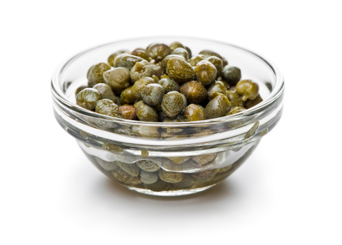 transparent bowl of marinated capers isolated on white. More pictures...