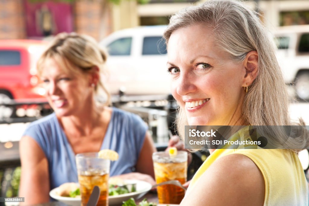 Donna guardando indietro avendo pranzo in ristorante all'aperto - Foto stock royalty-free di Abbigliamento casual