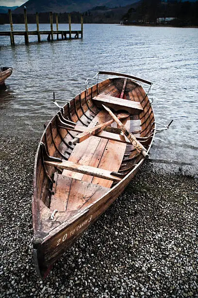 Rowing boat on shingle beach at Derwent Water - Dramatic cloudscape and a grainy retro/old style film look