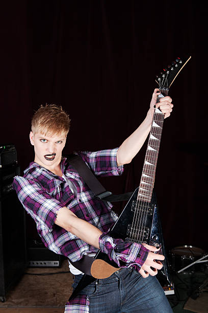 istock Guitar playing punk rocker with dark lipstick and torn shirt 182835092