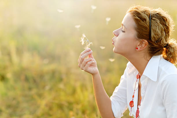 istock Young woman blowing a dandelion 182835582