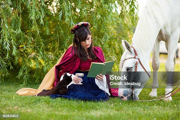 Mujer Joven Usando Renaissance Vestido Lectura Por Debajo De Árbol Con Caballos Foto de stock y más banco de imágenes de Renacimiento