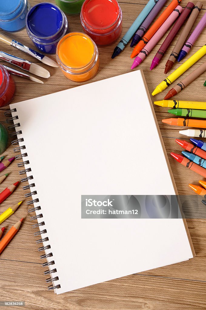 School supplies with blank book "Blank white notebook on a school desk with various paints, crayons and pencils.  Alternative version shown below:" Above Stock Photo
