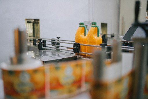 Production line of bottled juice beverage moving on conveyor belt in factory