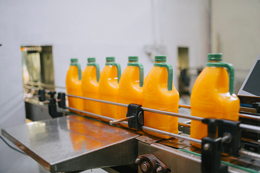 Production line of bottled juice beverage moving on conveyor belt in factory
